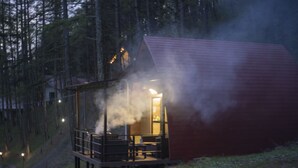 Una cabaña con fachada de madera, un balcón y humo saliendo de la chimenea.
