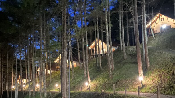 Una propiedad en una ladera con varias construcciones, un camino pavimentado y una valla.