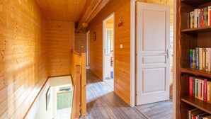 Un intérieur en bois avec une bibliothèque, une porte et un couloir menant à une autre pièce.