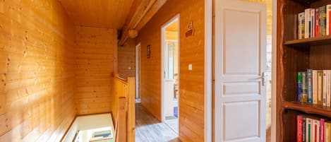 Un interior de madera con una estantería, una puerta y un pasillo que conduce a otra habitación.