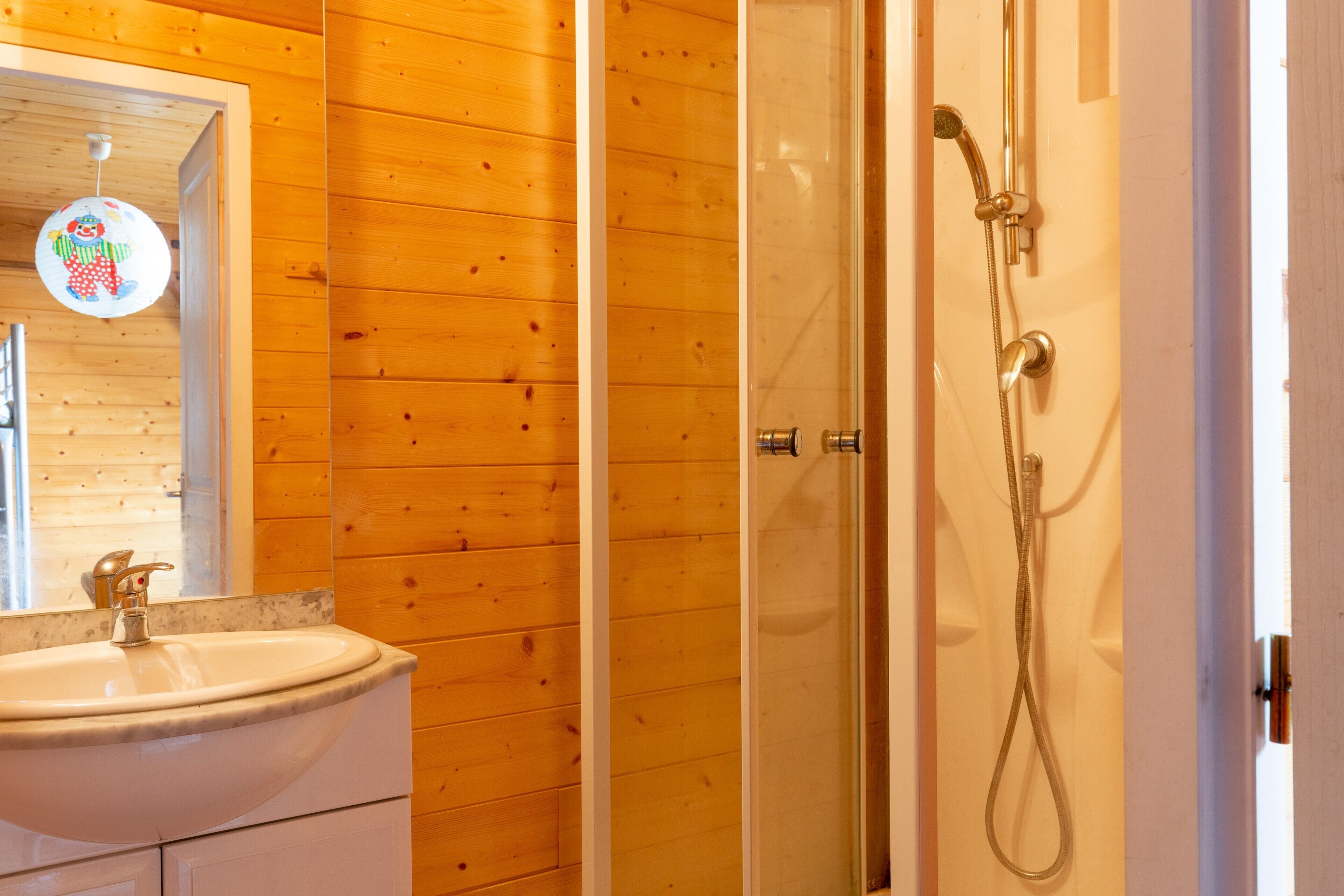 A bathroom with a wooden wall, a sink, and a shower.