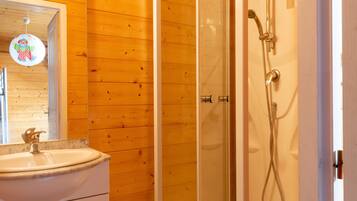 A bathroom with a wooden wall, a sink, and a shower.