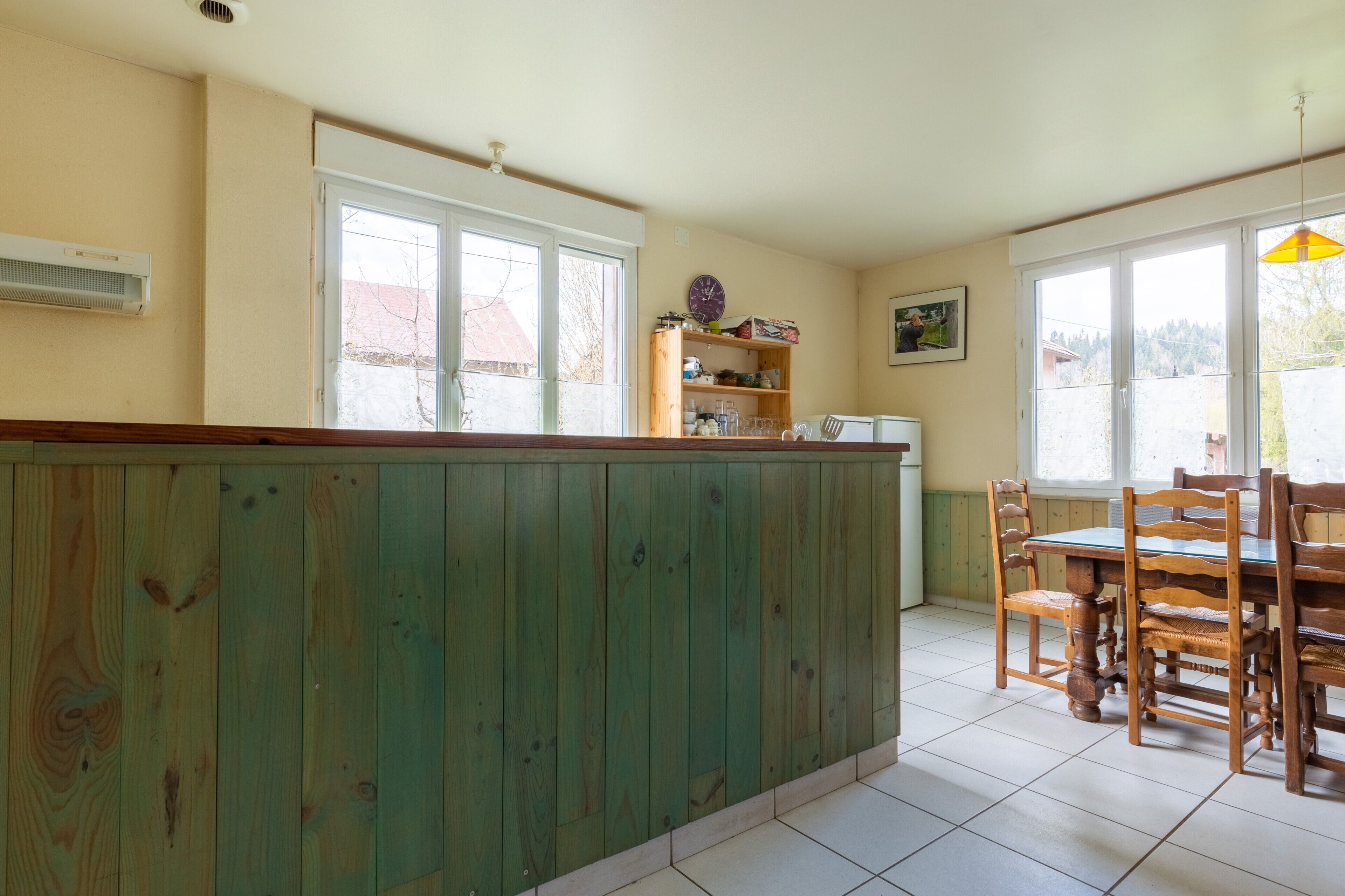 Una cocina con una isla de madera, una mesa de comedor con sillas y una ventana con vistas al exterior.