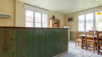 Una cocina con una isla de madera, una mesa de comedor con sillas y una ventana con vistas al exterior.