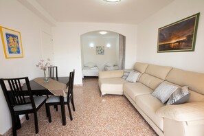 Uma sala de estar com um sofá, uma mesa de jantar com cadeiras e um quadro na parede.