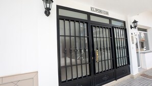 Une façade d’immeuble avec un grand portail noir, une enseigne indiquant « EL PERDICION », et une lanterne fixée au mur.