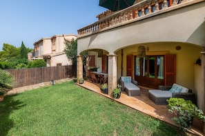 A house with a patio, outdoor furniture, and a well-maintained lawn.