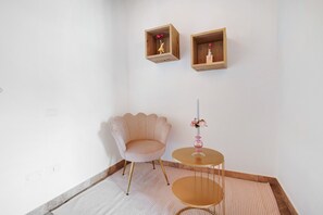 A corner room with a pink chair, two wooden shelves with figurines, a small round table with a vase, and a striped rug. - Holiday Apartment "Casale La Coccinella Lavanda" with Shared Garden, A/C & Wi-Fi (Caprino Veronese)