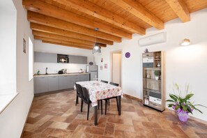 A kitchen with a microwave, sink, and cabinets, a dining table with chairs, a wooden ceiling, and a potted plant. - Holiday Apartment "Casale La Coccinella Lavanda" with Shared Garden, A/C & Wi-Fi (Caprino Veronese)