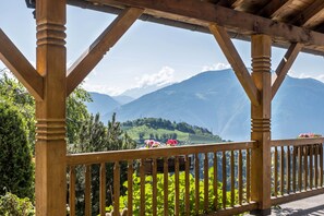 A wooden pergola with a view of mountains and greenery.