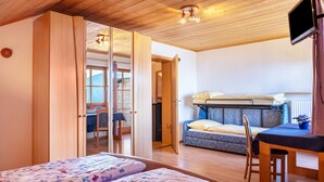 A room with a bed, a desk, a chair, and a television. - Apartment 'Weingartnerhof Calendula' with mountain view, shared terrace and Wi-Fi (Jenesien)