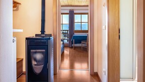 A hallway leading to a room with a bed, a window with a view, and a wood-burning stove. - Apartment 'Weingartnerhof Calendula' with mountain view, shared terrace and Wi-Fi (Jenesien)