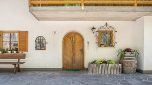 A stone-floored entrance with a wooden door, a bench, and potted plants. - Apartment 'Weingartnerhof Calendula' with mountain view, shared terrace and Wi-Fi (Jenesien)