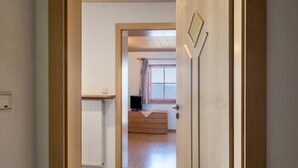 Un pasillo que conduce a una habitación con un radiador, un aparador de madera y una ventana con cortinas.