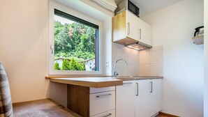 A kitchen with a window, white cabinets, a wooden countertop, and a stainless steel sink. - Studio Apartment "Talblick 2" with Mountain View, Garden and Wi-Fi (Lajen)