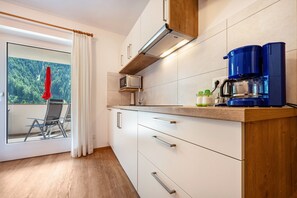 A modern kitchen with a microwave, coffee maker, and wooden countertop.