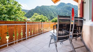 Ein Balkon mit Blick auf Berge, einem Holzzaun und einem Metallstuhl.