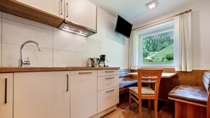 Eine kompakte Küche mit Einbauherd, Spüle und Fenster mit Blick auf eine grüne Landschaft.