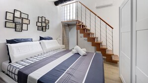 A bedroom with a bed, a staircase, and framed pictures on the wall.