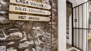 A stone wall with wooden signs indicating 'CASA VAGANZE,' 'DOLCE SOGGIORNO,' and 'HOST DANIELA.'