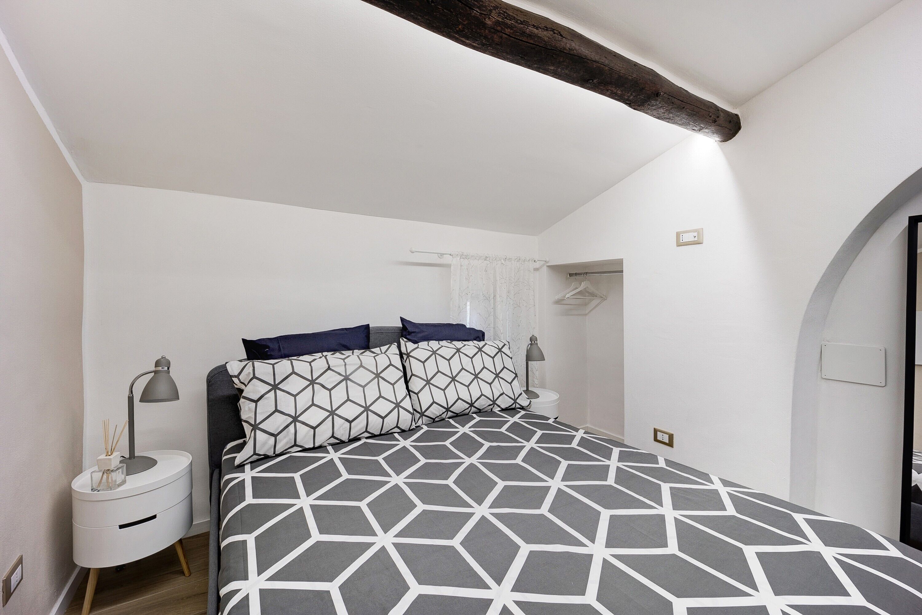 Een slaapkamer met een bed, nachtkastjes, een lamp en een raam met gordijnen.