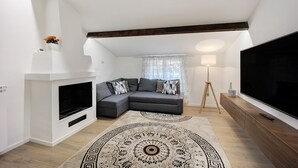 A modern living room with a sectional sofa, a fireplace, a large TV, and a patterned rug.