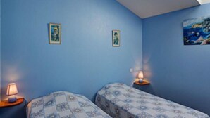Une chambre avec deux lits, une lucarne et un tableau au mur.