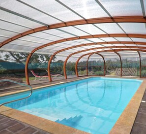 Una piscina techada con techo de vidrio, rodeada por un marco de madera.