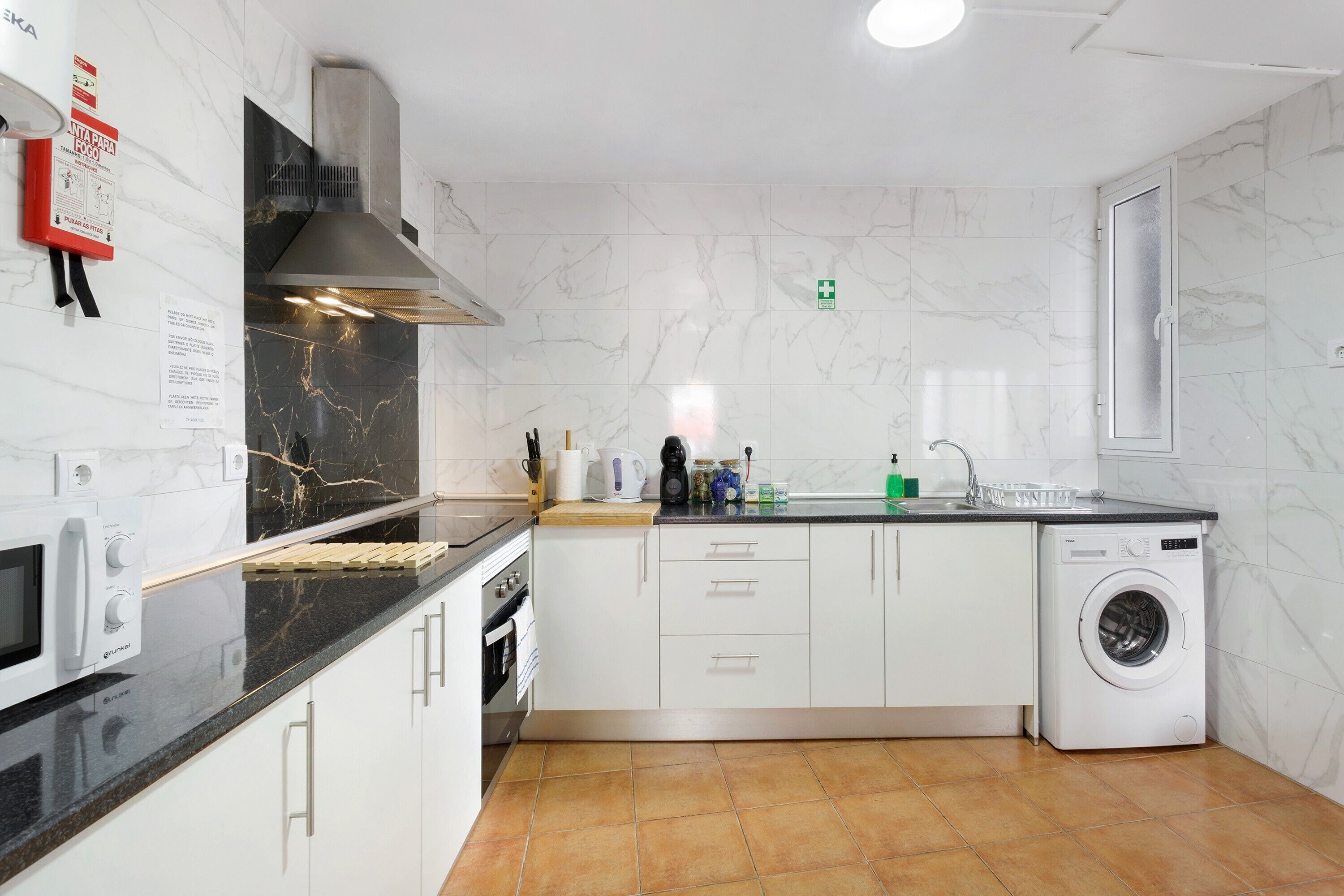 A modern kitchen with a built-in microwave, stove, and washing machine.