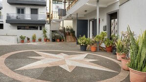 Un patio con pavimento en forma de estrella, plantas en macetas, una escalera y un edificio con balcones.