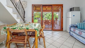 A dining area with a table set for four, wooden chairs, a staircase, and a sliding glass door leading to an outdoor patio.