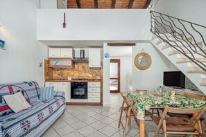 A compact living space with a kitchenette, a dining area, and a staircase.