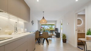 A modern kitchen with a large island, dining area with chairs, and a view of the outdoors. - Apartment 'Pelicano' with Sea View, Wi-Fi and Air Conditioning (Cambrils)