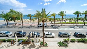 A coastal street with parked cars, palm trees, and a view of the sea. - Apartment 'Pelicano' with Sea View, Wi-Fi and Air Conditioning (Cambrils)