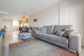 A modern living room with a grey sofa, ottoman, and patterned rug.