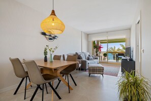 A modern living room with a dining area, a sofa, and a television.
