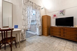 A room with a desk, chair, wardrobe, television, and a door with patterned curtains. - Holiday Apartment "Chiarina Rooms" with A/C & Wi-Fi (Polignano a mare)