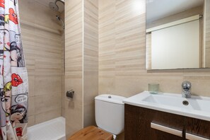 A bathroom with a shower, toilet, sink, and mirror.
