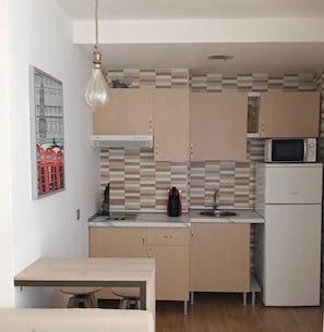 A compact kitchen with a microwave, sink, and a hanging light fixture. - Studio Apartment 'Torremolinos' with Shared Pool, Shared Garden & Wi-Fi (Málaga)