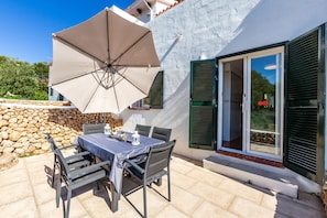 Un patio al aire libre con una mesa, sillas y un gran paraguas.