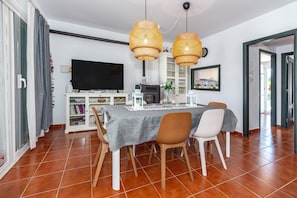 Un comedor con una mesa, sillas, televisor, armario y chimenea.