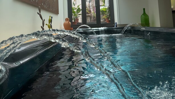 Un área de spa con hidromasaje, techo con tragaluces y una pared con un cartel.