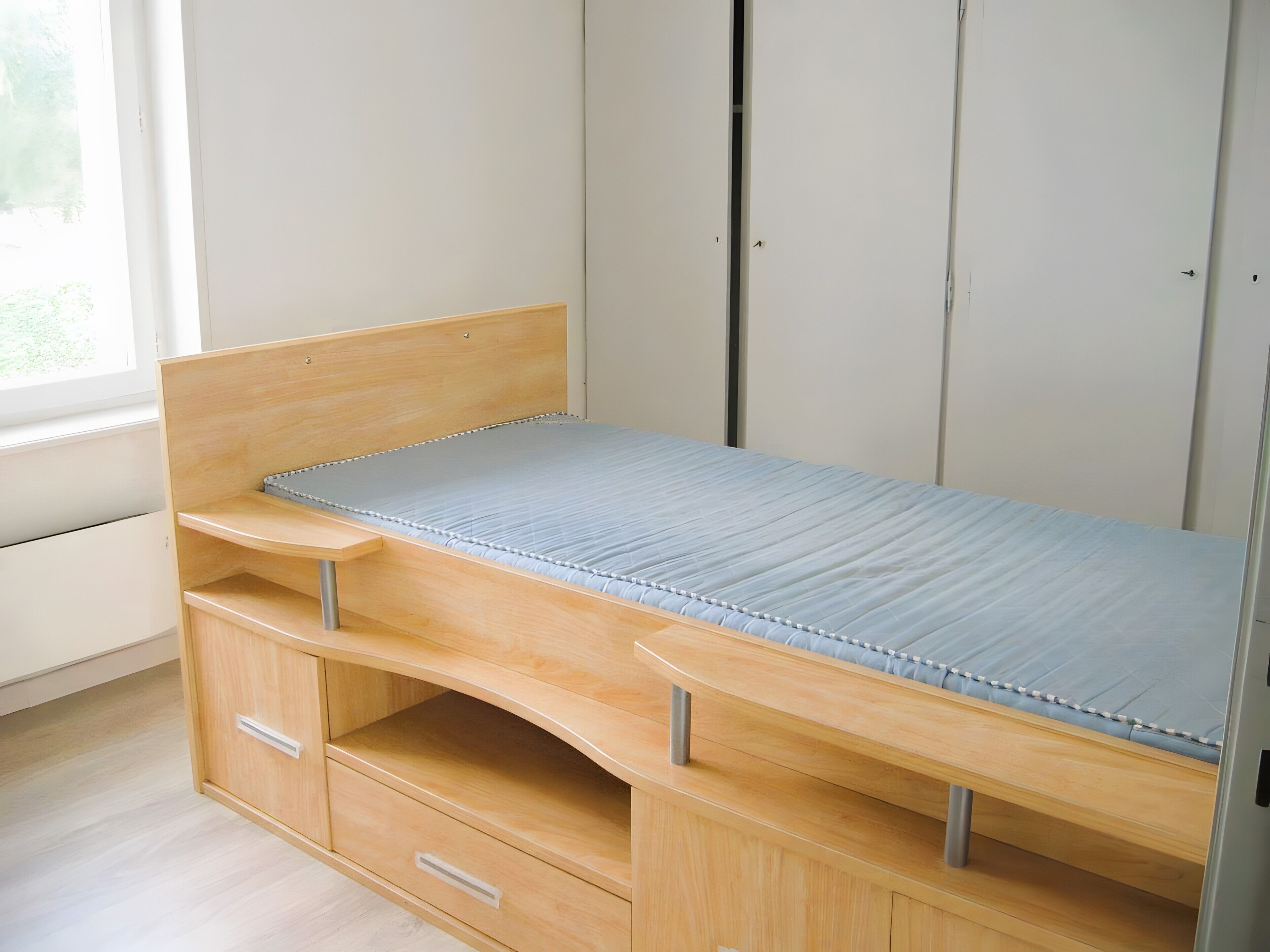 Un lit simple avec un cadre en bois et des tiroirs de rangement situés en dessous.