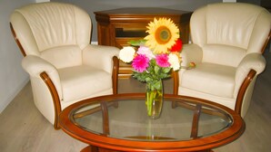 A room with two leather armchairs, a glass coffee table, and a wooden side table with a vase of flowers. - Apartment 'Les Racines De La Vie Rurale' with Wi-Fi and Air Conditioning (LEDRINGHEM)