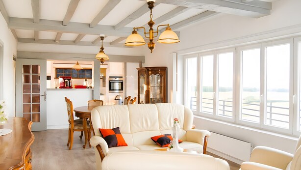 A spacious living area with a large window, a dining table, and a kitchen in the background. - Apartment 'Les Racines De La Vie Rurale' with Wi-Fi and Air Conditioning (LEDRINGHEM)