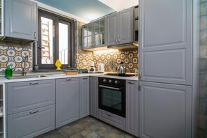 Une cuisine avec des meubles de couleur grise, une cuisinière et une fenêtre donnant sur un beau paysage.