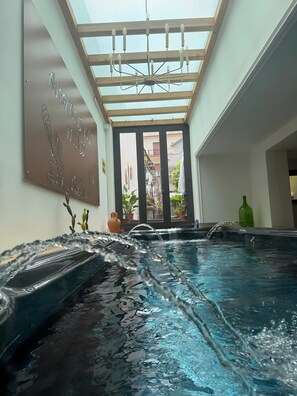 A spa area with a hot tub, a ceiling with skylights, and a wall with a sign.