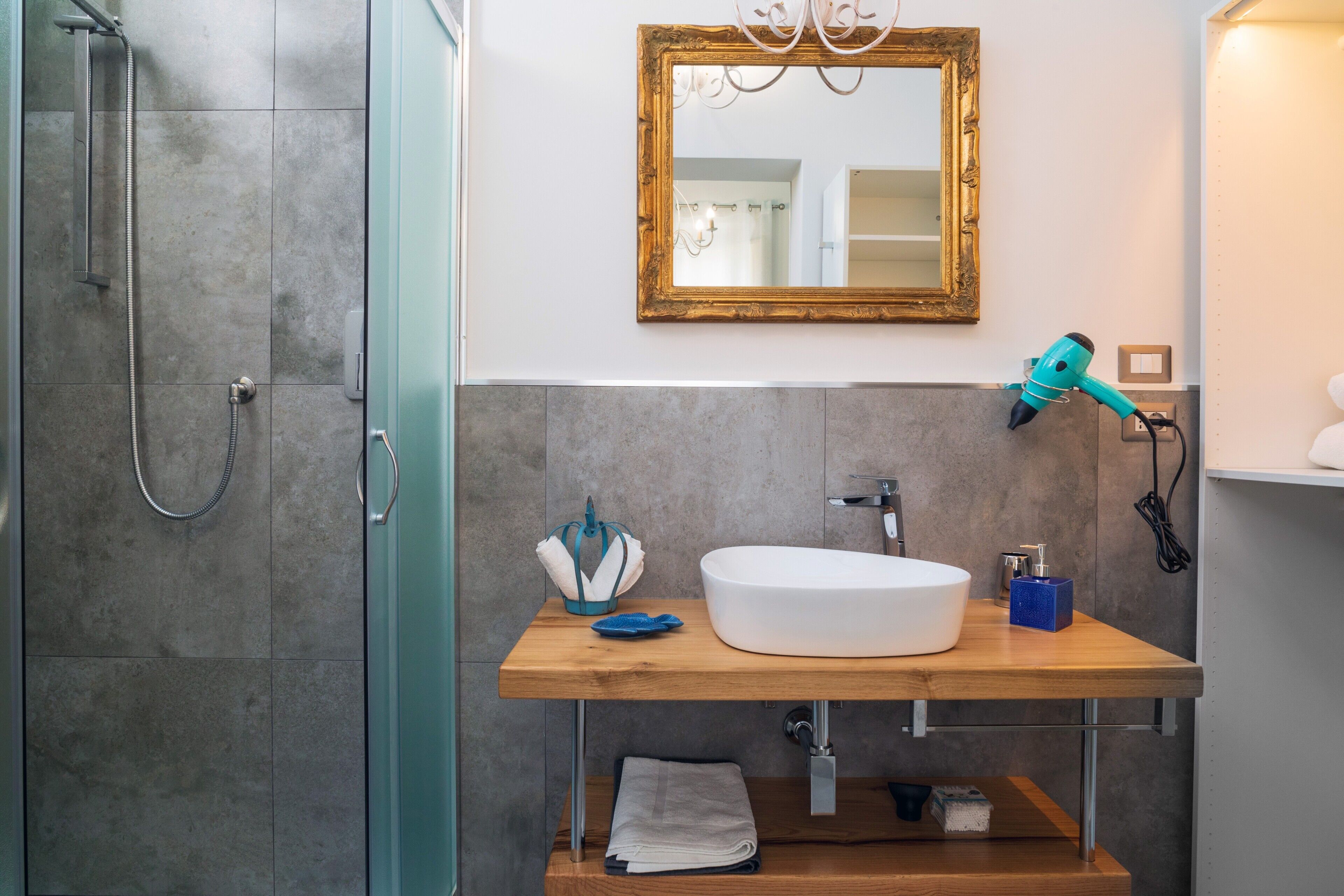 Une salle de bain équipée d’une douche, d’un lavabo, d’un miroir et d’un sèche-cheveux.