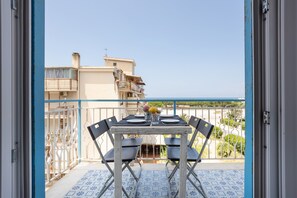 A balcony with a table set for two, a railing, and a view of the sea. - Holiday Apartment "The View Of The Sea" near Beach with 2 Balconies & Wi-Fi (Capaci)