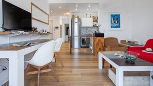 Una sala de estar moderna con televisor, comedor, cocina y sofá rojo.